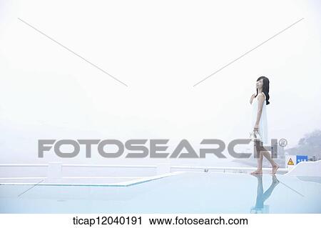 A woman in white dress walking on the edge of a pool on bare feet View Large Photo Image Stock Image - A woman in white dress walking on the edge of a pool on bare feet. Fotosearch