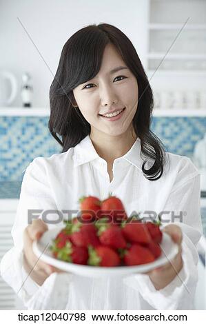 A woman in white shirt handing in a plate of strawberries gto camera View Large Photo Image Stock Photo - A woman in white shirt handing in a plate of strawberries gto camera . Fotosearch