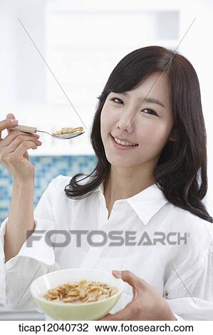 A woman in white shirt holding a spoon with cereal View Large Photo Image Stock Image - A woman in white shirt holding a spoon with cereal. Fotosearch