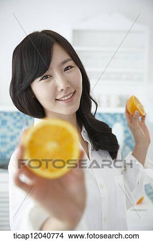 A woman in white shirt holding oranges in a kitchen View Large Photo Image Picture - A woman in white shirt holding oranges in a kitchen. Fotosearch