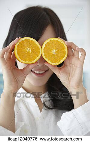 A woman in white shirt putting oranges in front of her eyes View Large Photo Image Stock Photograph - A woman in white shirt putting oranges in front of her eyes. Fotosearch