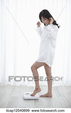 A woman in white shirt weighing herself View Large Photo Image Stock Photo - A woman in white shirt weighing herself. Fotosearch