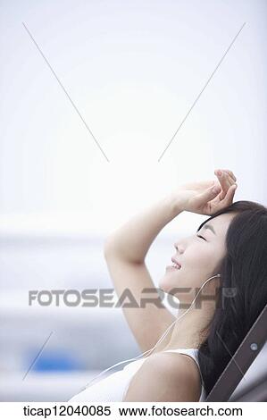 Stock Photography - A woman listeing to a music with a hand on her forehead. Fotosearch