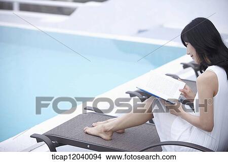 A woman reading a book on a sunbed smiling View Large Photo Image Picture - A woman reading a book on a sunbed smiling. Fotosearch
