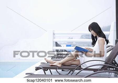 A woman reading a book while sat on a sunbed View Large Photo Image Stock Image - A woman reading a book while sat on a sunbed. Fotosearch