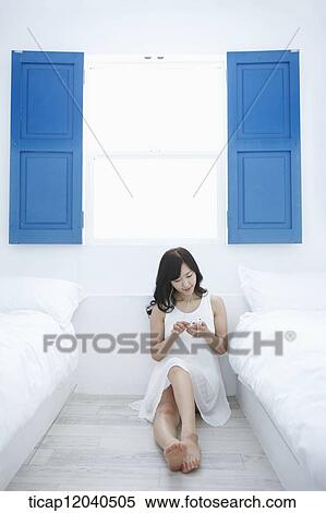 A woman sitting on a floor in a room listening to a music View Large Photo Image Stock Photography - A woman sitting on a floor in a room listening to a music. Fotosearch