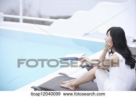 A woman with a book in her hand looking at a pool View Large Photo Image Stock Photo - A woman with a book in her hand looking at a pool. Fotosearch