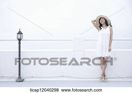 A woman with a white dress and a sun hat leaning on a white fence View Large Photo Image Stock Photo - A woman with a white dress and a sun hat leaning on a white fence. Fotosearch