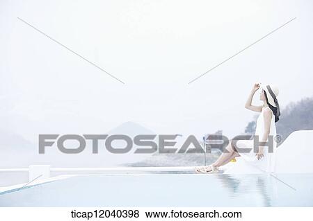 A woman with a white dress and a sun hat sitting next to a swimming pool View Large Photo Image Stock Photo - A woman with a white dress and a sun hat sitting next to a swimming pool. Fotosearch