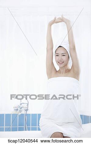 A woman with bath towel around body and over head sitting at edge of bath tube View Large Photo Image Picture - A woman with bath towel around body and over head sitting at edge of bath tube. Fotosearch