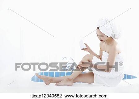 A woman with bath towel around her body and over head sitting at edge of bath tub putting lotion on her leg View Large Photo Image Stock Image - A woman with bath towel around her body and over head sitting at edge of bath tub putting lotion on her leg. Fotosearch