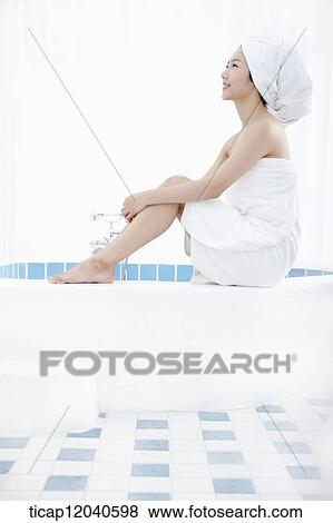 A woman with bath towel around her body sitting with two feet on a edge of a bathtub View Large Photo Image Stock Photo - A woman with bath towel around her body sitting with two feet on a edge of a bathtub. Fotosearch
