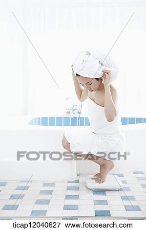 A woman with bath towel around her body and over head weighing herself with two feet on a scale View Large Photo Image Stock Photo - A woman with bath towel around her body and over head weighing herself with two feet on a scale. Fotosearch