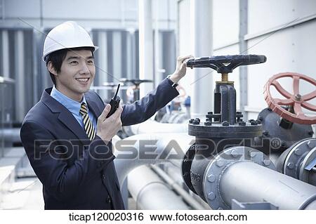 Stock Photograph - An architect chekcing pipleline with a radio receiver in his hand. Fotosearch