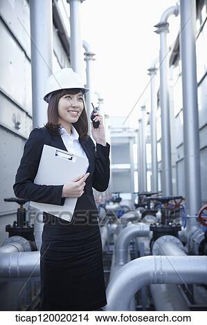 An architect in hardhat answering radio receiver, holding a report in her arm View Large Photo Image Picture - An architect in hardhat answering radio receiver, holding a report in her arm. Fotosearch