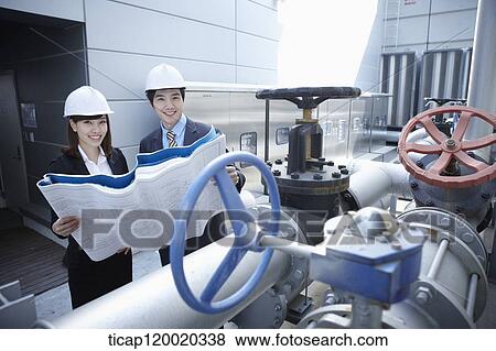 Stock Photo - Architects smiling while looking at a pipeline valve. Fotosearch