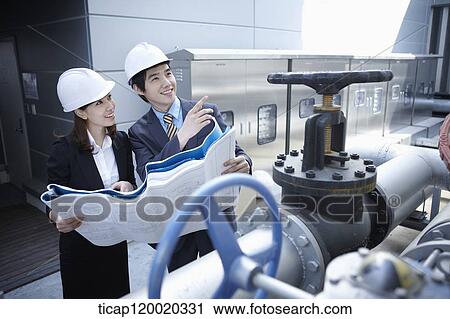 Architects wearing hardhats looking at blueprints View Large Photo Image Stock Image - Architects wearing hardhats looking at blueprints . Fotosearch