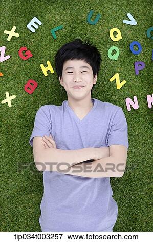 Stock Photo - boy lying on the ground with his arms folded . Fotosearch