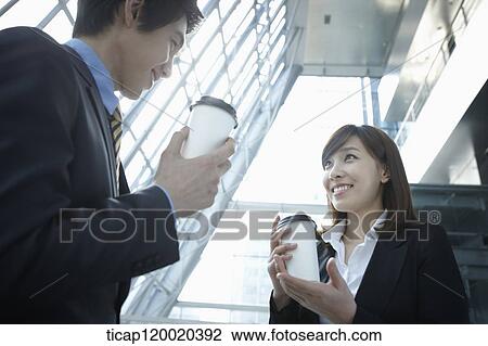 Businessman and woman discussing with coffee in their hands View Large Photo Image Stock Image - Businessman and woman discussing with coffee in their hands. Fotosearch