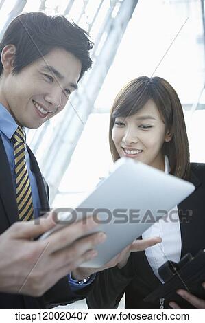 Stock Photo - Businessman and woman looking at report in a building . Fotosearch