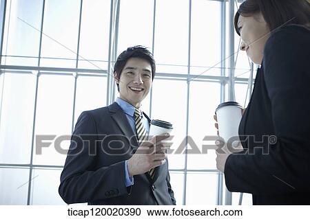 Stock Image - Businessman and woman smiling wile drinking coffee. Fotosearch