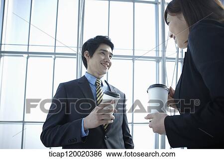 Stock Photograph - Businessman and woman talking while drinking take out coffee. Fotosearch