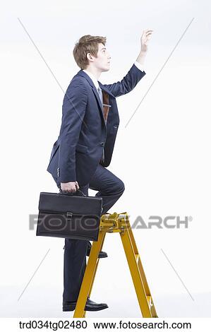 Stock Image - businessman reaching out his hand on the ladder. Fotosearch