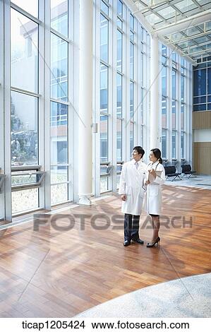 Picture - Doctors in a white dressing gown looking out at windows in a building. Fotosearch