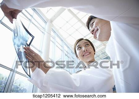 Doctors in a white dressing gown happily talking about a x-ray picture View Large Photo Image Stock Image - Doctors in a white dressing gown happily talking about a x-ray picture . Fotosearch