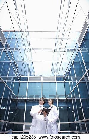 Doctors looking up in a modern building View Large Photo Image Stock Photography - Doctors looking up in a modern building . Fotosearch