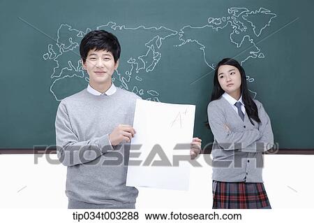 girl leaning against the blackboard and boy holding a paper View Large Photo Image Stock Photo - girl leaning against the blackboard and boy holding a paper. Fotosearch