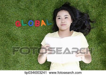 girl lying on the ground and holding a book View Large Photo Image Stock Image - girl lying on the ground and holding a book . Fotosearch
