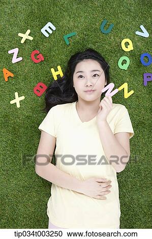 Stock Image - girl lying on the ground and holding a letter of N. Fotosearch