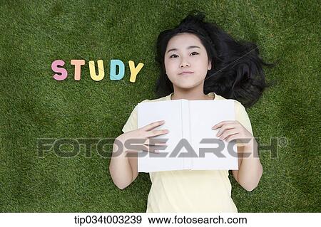 girl lying on the ground and holding a book View Large Photo Image Stock Photo - girl lying on the ground and holding a book . Fotosearch