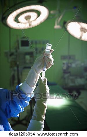 Injecting the sringe needle into a bottle of medication in surgery room View Large Photo Image Picture - Injecting the sringe needle into a bottle of medication in surgery room. Fotosearch