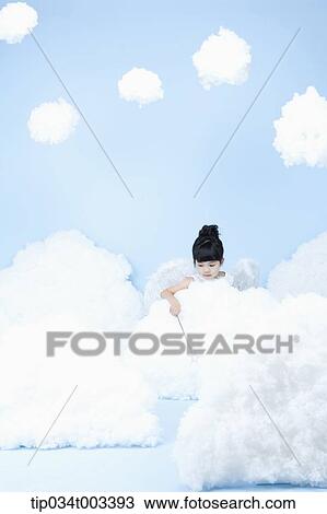 Stock Image - little girl looks of angel on the clouds. Fotosearch