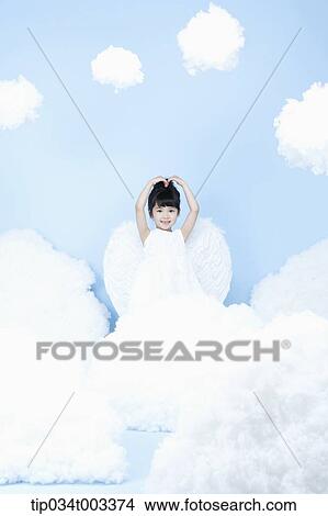 Picture - little girl with looks of angel on the clouds. Fotosearch