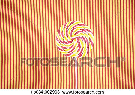 Stock Image - lollipop in the red and yellow stripped background. Fotosearch