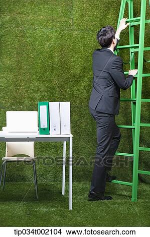 man climbing the ladder next to the desk View Large Photo Image Picture - man climbing the ladder next to the desk. Fotosearch