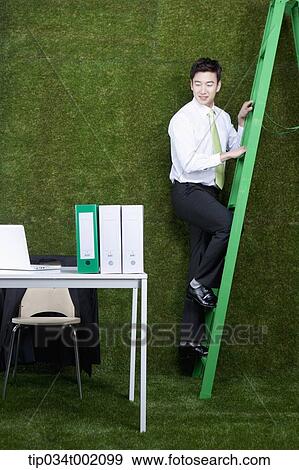 man climbing the ladder next to the desk View Large Photo Image Stock Photo - man climbing the ladder next to the desk. Fotosearch