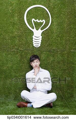 Picture - man coming up with idea under the bulb. Fotosearch