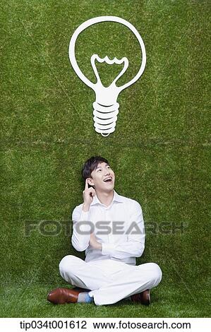 Stock Image - man coming up with idea under the bulb. Fotosearch