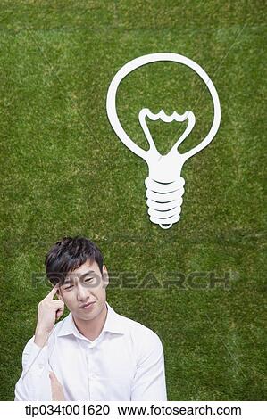 Stock Image - man coming up with idea under the bulb. Fotosearch