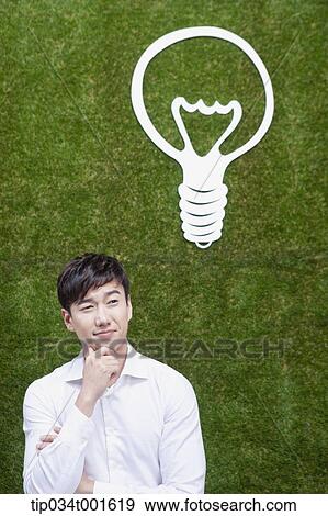 Stock Photo - man coming up with idea under the bulb. Fotosearch