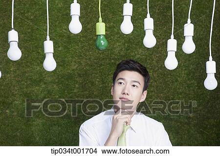 Picture - man coming up with idea under the bulbs hanging on the ceiling . Fotosearch