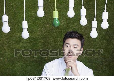Stock Photo - man coming up with idea under the bulbs hanging on the ceiling . Fotosearch
