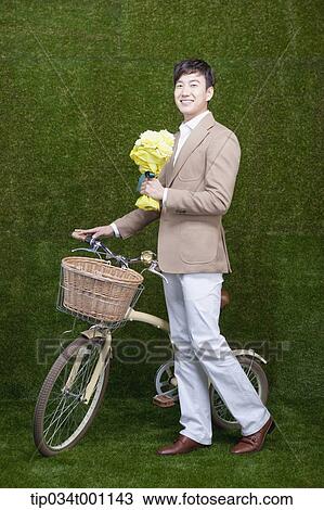Stock Image - man holding a bouquet next to the bike. Fotosearch
