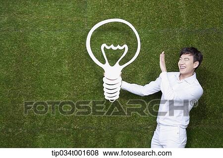 Stock Photo - man holding a bulb on his hand. Fotosearch