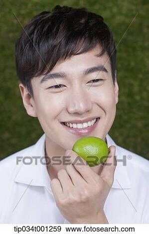 Stock Photo - man holding a green citrus . Fotosearch