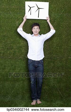 Picture - man holding a paper cut of pinwheel over his head. Fotosearch